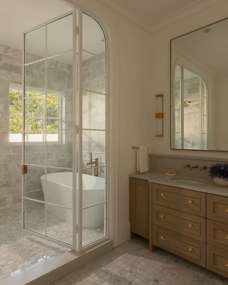 Arched glass, hand-selected stone and warm brass in a primary ensuite.